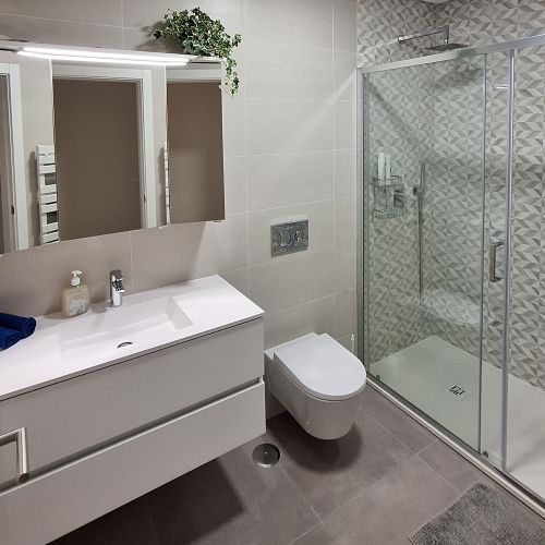 A bathroom with a white mirror cabinet and a large shower.