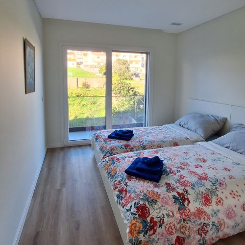 A bedroom with a double bed and a blue painting on the wall.