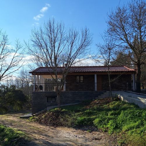 An exterior view of the holiday apartment with trees and a natural, unpaved driveway.