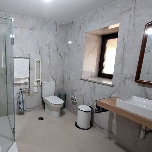 A bathroom with gray tiles, a brown mirror cabinet, and a shower