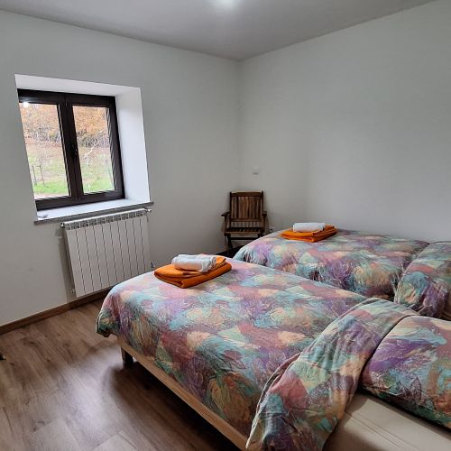 A bedroom with two single beds and a wooden chair